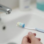 Person cleaning dentures with a toothbrush.