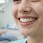 Smiling woman with natural-looking teeth in a dental clinic, illustrating what dental bridges are for teeth